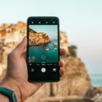 person holding a phone near cliff during daytime