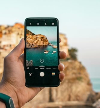 person holding a phone near cliff during daytime