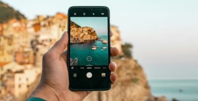 person holding a phone near cliff during daytime